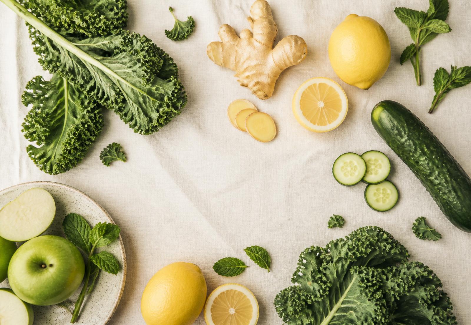 Flat lay of kale, ginger, lemons, cucumber, apples and mint